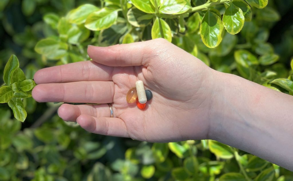 Hand holding group of vitamins and supplements