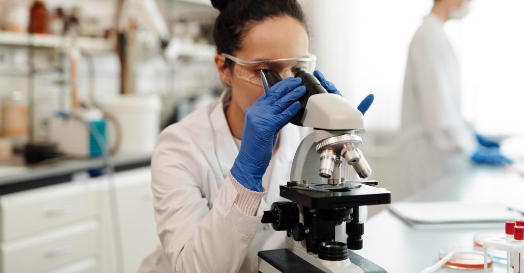 Scientist in a lab looking through microscope