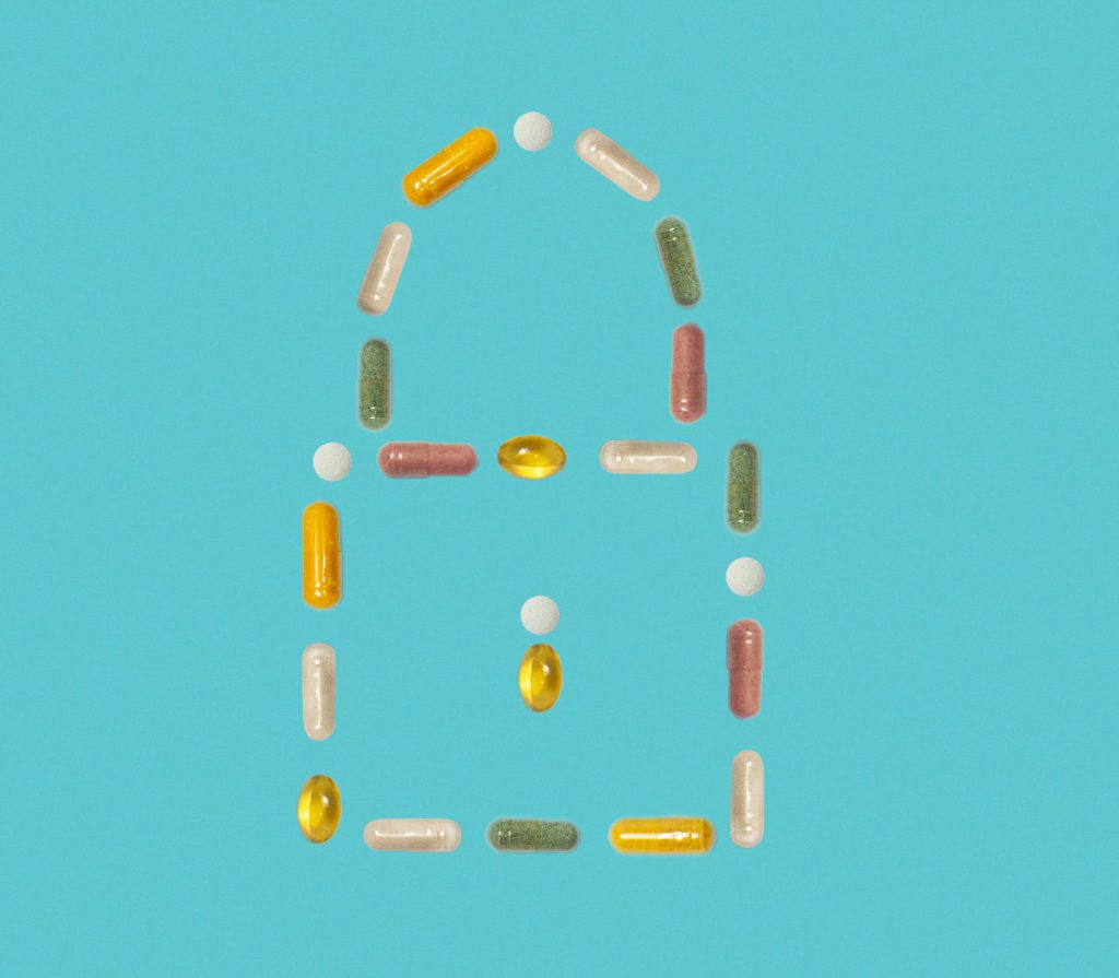 Multi-colored pills in shape of a lock on blue background