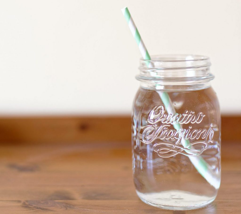 A mason jar filled with water and a green straw
