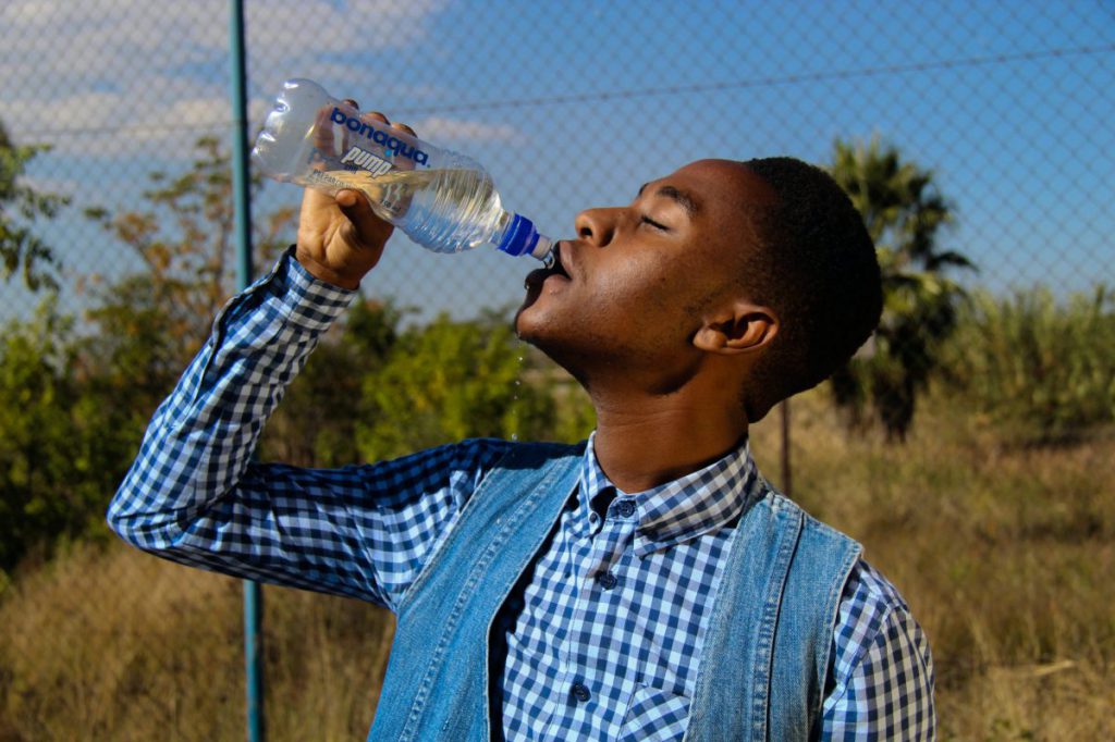 Man outside drinking out of a water bottle