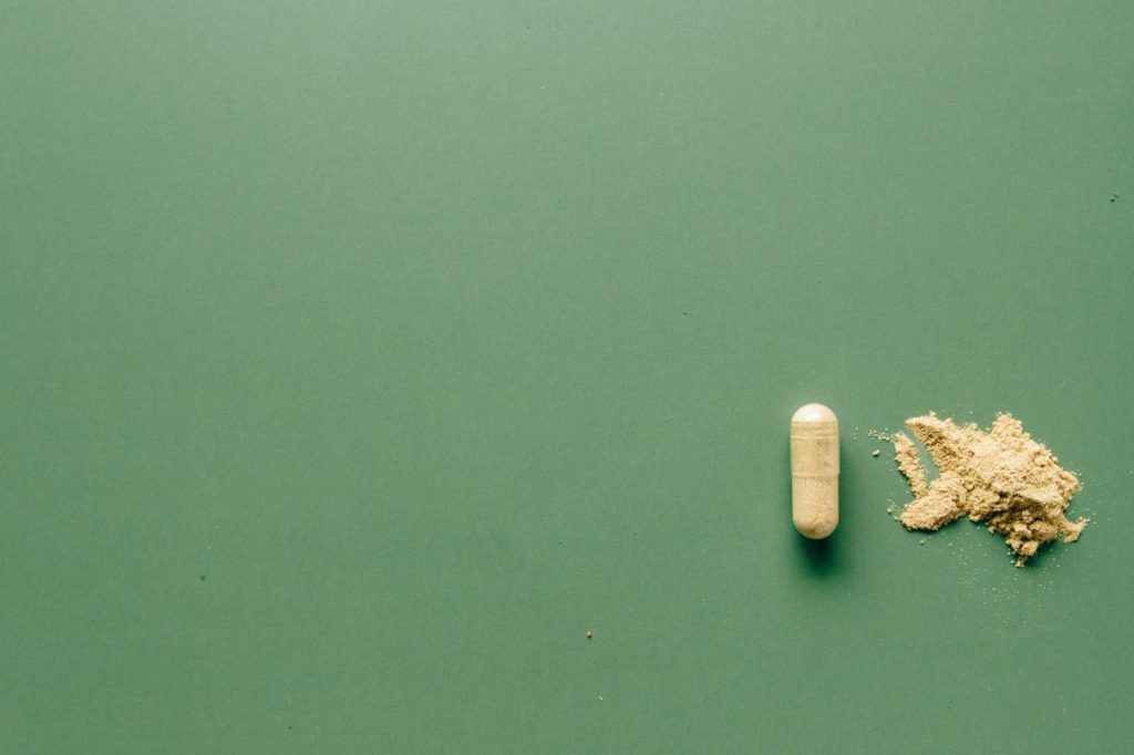 Beige pill and beige crushed pill on green background