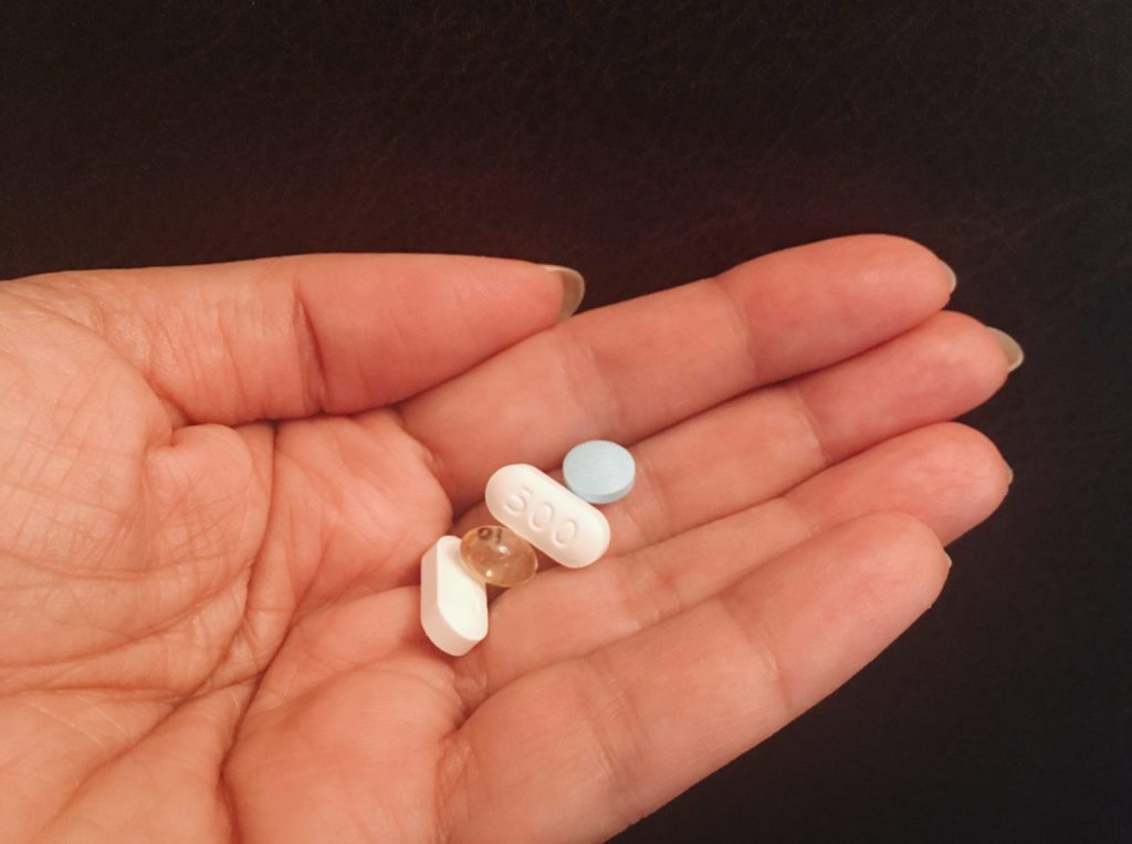 Hands holding four different pills 