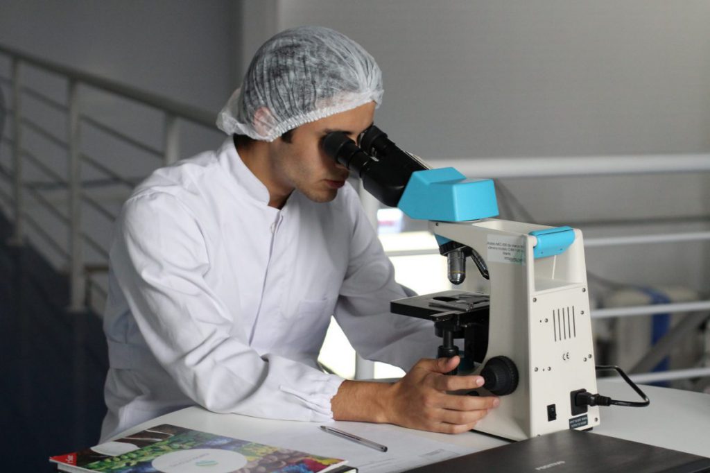 Scientist looking through microscope in lab