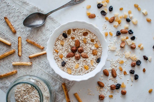 Two bowls of oatmeal on the counter surrounded by various cut up fruit. 