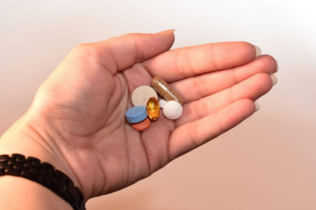 Hand holding group of pills capsules.