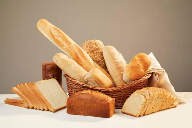 Various different types of breads, cut, whole, baguettes, some in a basket