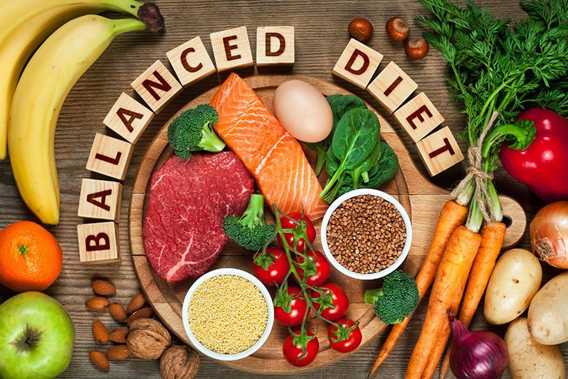 Balanced diet image and scrabble pieces, surrounded by fruits and vegetables